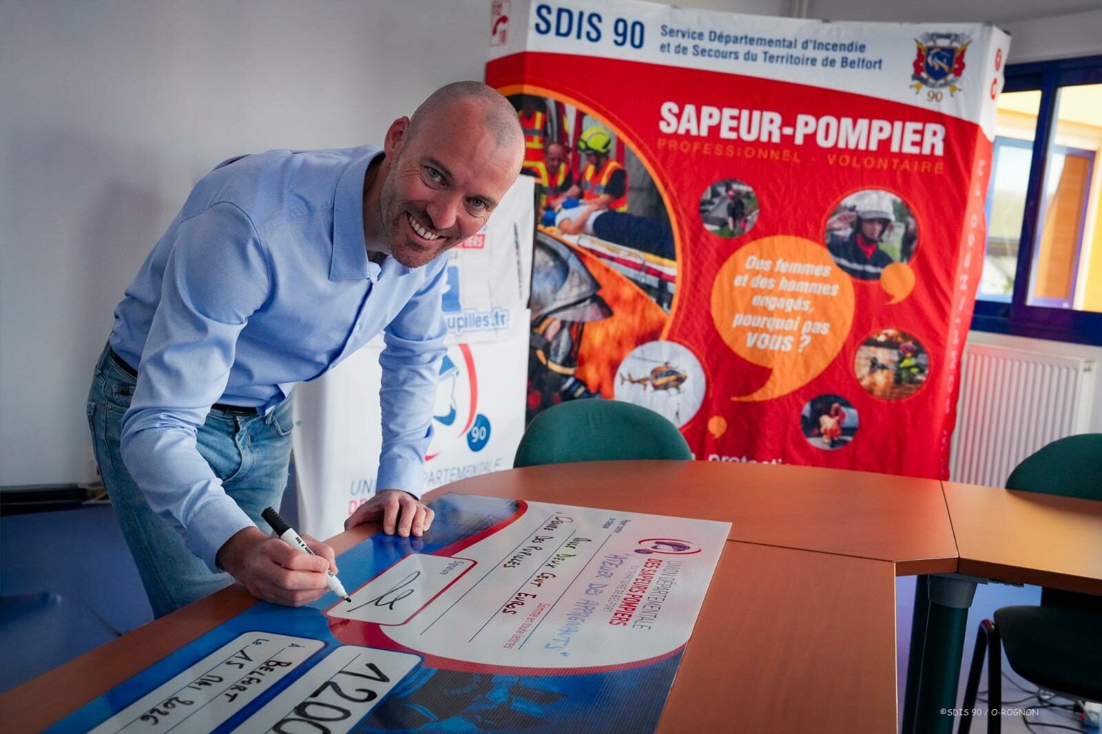 Laurent Scarabin signe le chèque de 1 200 euros destiné à l'Œuvre des Pupilles des Sapeurs-Pompiers, au SDIS 90 à Belfort, le 15 mai 2026